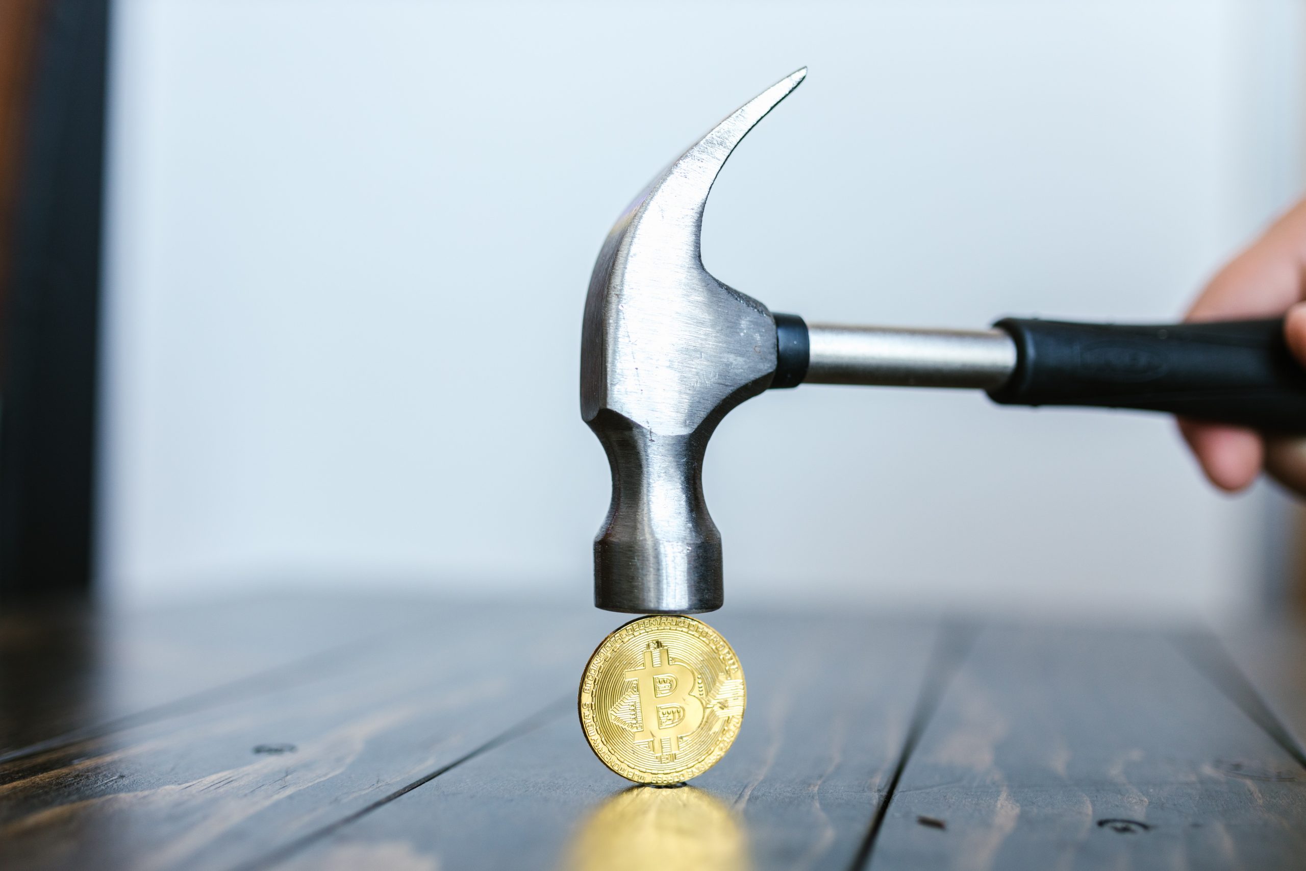 someone holding a hammer over a bitcoin